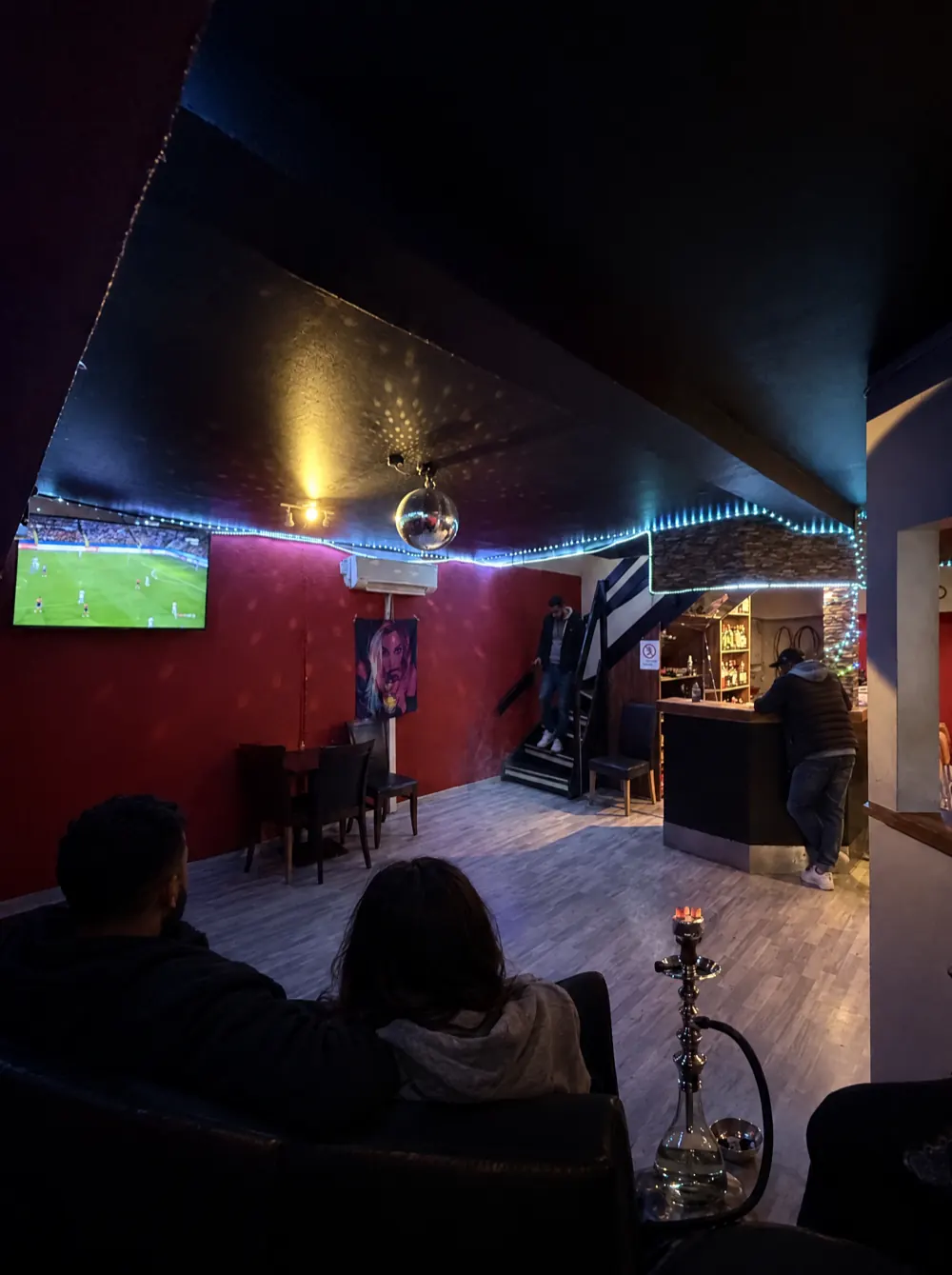 Sen aften i loungen: diskokuglen lyser, et par sidder i sofaen, og en vandpibe står klar