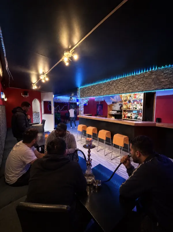 Ved bordet: venner deler en vandpibe med baren i baggrunden